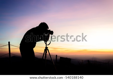 Photographer silhouette above a clouds sea, misty mountains in twilight time