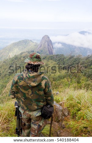 Nature photographer with digital camera on top of the mountain