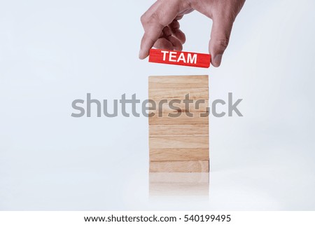 Business man holding red wood block with Team letter. Team work concept.