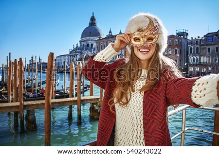 Another world vacation. Portrait of smiling elegant woman in fur hat in Venice, Italy taking selfie while in Venetian mask Royalty-Free Stock Photo #540243022