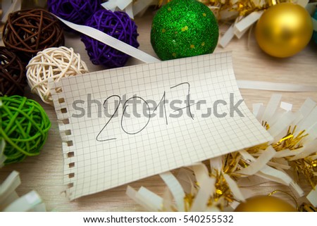 Leaf from a notebook in the box with the inscription 2017 on the background of Christmas decorations, balls, tinsel, ribbons