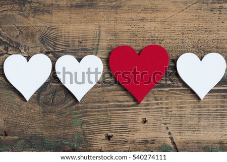 Three white and one red heart on old wood background.Card on Valentine's Day
