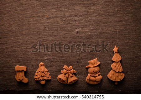 Homemade new year chocolate figures on a black slate table. Toned.