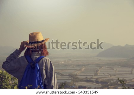 Hipster girl with backpack enjoying on peak of foggy mountain, tourist traveler taking pictures of amazing landscape on vintage photo