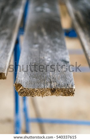 End of a plank of weathered rustic wood or timber on an outdoor frame in a close up selective focus view of the texture