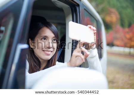 Woman taking photo outside a car