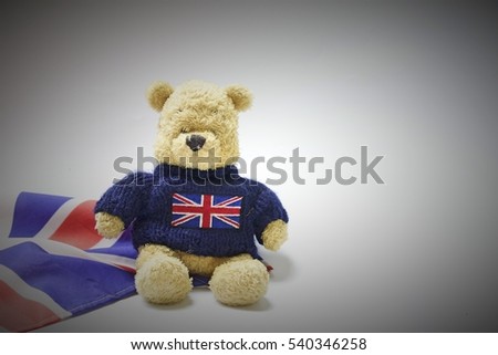Bear sits near Union Jack flag. Idea of London or Great Britain theme , focus on bear.
