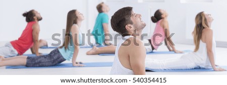 Panoramic picture of a small group of relaxed people practicing yoga together