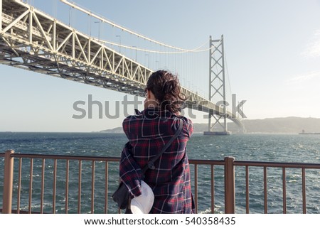 Woman Taking a Photo of the famous Akashi Kaikyo Bridge in Kobe, Kansai, Japan
