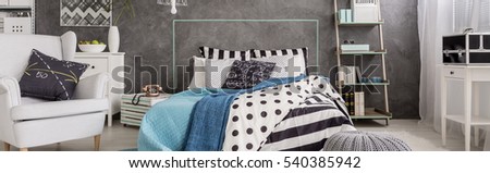 Stylish and cozy bedroom in grey tones with bed full of blankets