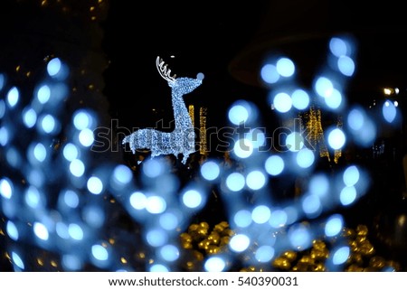 blue illuminated light of reindeer was decorated for Christmas event. circle bokeh look like snow fall in winter. It is beautiful image. natural light is used. 