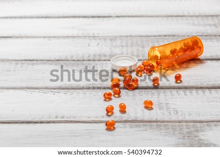 Omega 3 fish oil capsule with pill bottle on white wooden table. Health care and medical concept. copy space