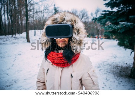 young woman getting experience in using VR-headset outdoor at winter park