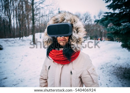 young woman getting experience in using VR-headset outdoor at winter park