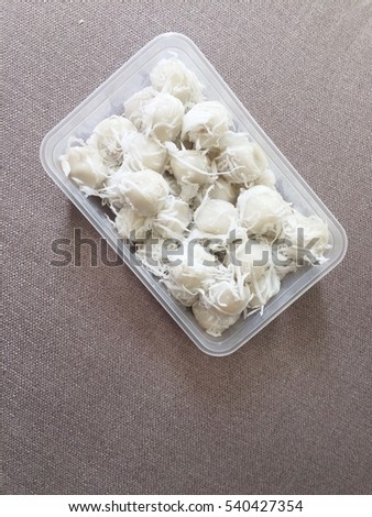 Sweet Sticky rice and coconut dumpling with caramelized coconut filling in the box on brown sofa with the area for your text in below of the picture