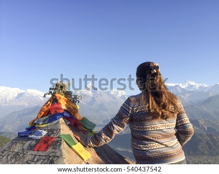 Female tourist facing the landscape of Annapurna Range during sunrise in Sarangkot, Nepal.