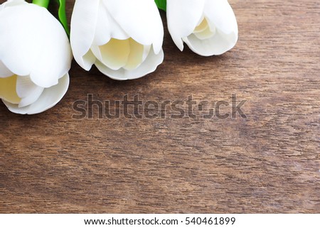Close up of three tulips on wooden table.