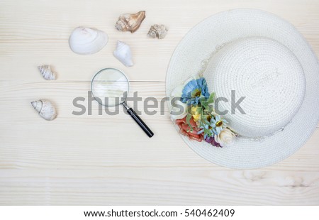 Hat bamboo weave decorated with flowers,shellfish and Magnifying glass on wood background