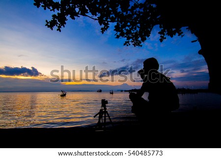 Photographer silhouette shooting sea outdoors at sunset .