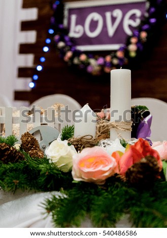 Love inscription on a wooden background, flashing lights, flowers. Candles and branch of pine
