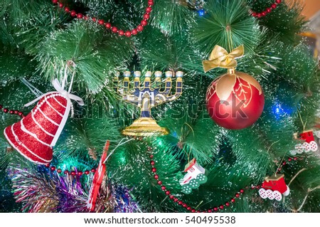 Jewish menorah beside the New Year toys on a Christmas tree. In December 2016 two holidays - Christmas and New Year coincide with the Jewish Hanukkah.
