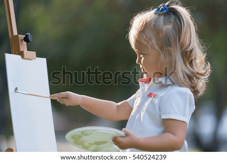 little girl draws a picture in park