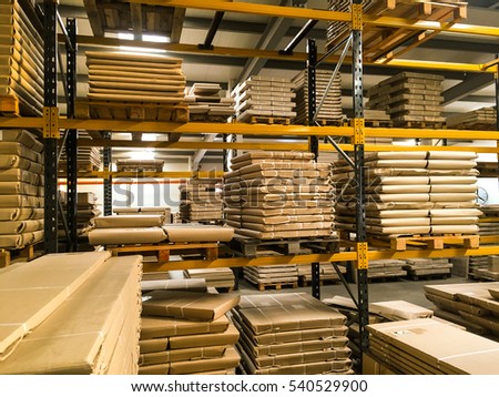 Shipment, logistics, delivery and product distribution business industrial concept: storage warehouse with row of stacked cardboard boxes with packed goods on wooden shipping pallets.