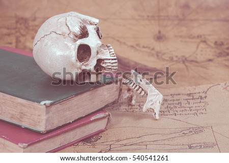 Human Skull and old text book on Old map Background