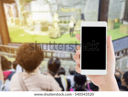 woman use mobile phone and blurred image of people on the grandstand look at the lion show in the night zoo of Chiang mai ,Thailand