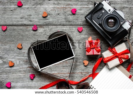 vintage retro camera on wood table background with blank photo in heart shape to placed your pictures, wooden hearts, gift boxes and notebook. valentines day background. top view
