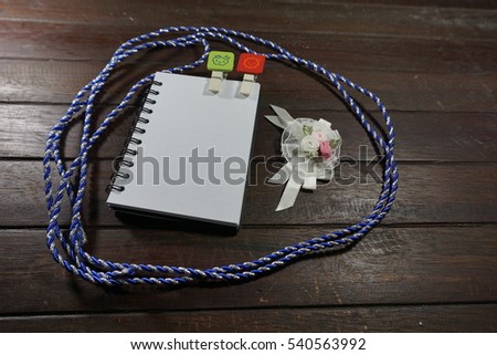 A blue rope, paper clips and a white cute ribbons on a wooden background. Blank note for placing your message.