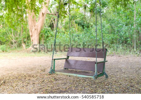 wooden classic outdoor hanging patio porch swing bench in the garden.
swing in the park - Bench under the tree.