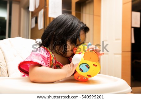 Cute happy Asian baby girl playing toy.