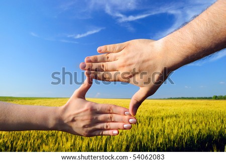 Hands form a rectangle against a wheaten field