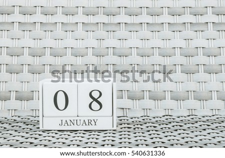 Closeup surface white wooden calendar with black 8 january word on blurred weave wood chair textured background with copy space , selective focus at the calendar