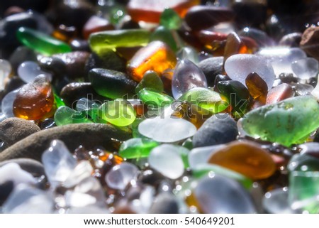 close up of a group of shiny pieces of sea glass on the beach using a star filter to obtain a sparkling effect