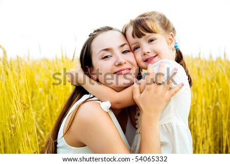 young mother and her daughter at the wheat field on a sunny day