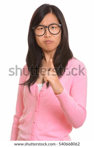 Young beautiful Asian nerd woman looking angry while pointing finger isolated against white background