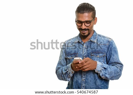 Young happy Indian man smiling and using mobile phone isolated against white background