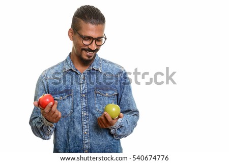 Young happy Indian man smiling and choosing between red and green apple isolated against white background