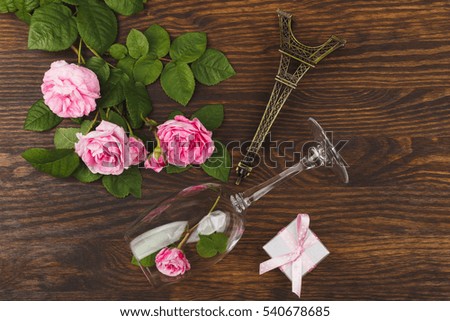Wineglass with light pink roses and decorations on the wooden background