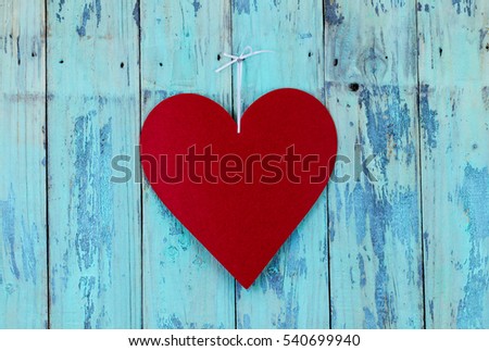 Blank red heart sign with hanging by white ribbon on antique rustic teal blue wood door; Valentines Day, Mothers Day and love concept with painted wooden copy space
