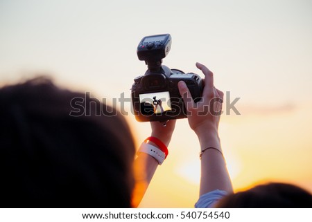 woman holding a camera in his hand and sunset photographs