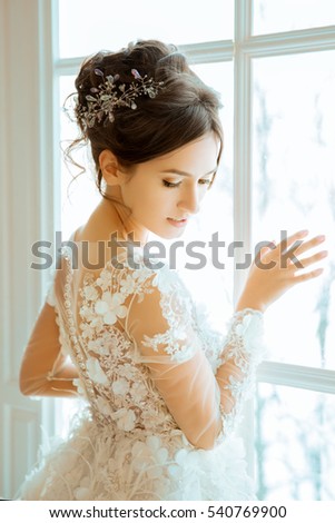 Bride. Wedding. The bride in a short dress with lace in the crown earrings. Wedding bouquet, makeup, hairstyle. Wedding Style