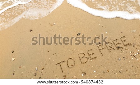 Handwriting words "TO BE FREE" on sand of beach