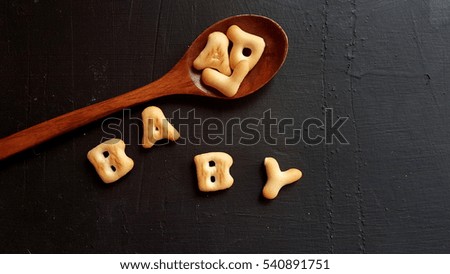 Letter cookies spell BABY on black background