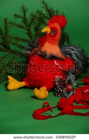 Rooster children's toy with spruce branch on a green background, symbol of 2017