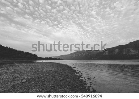 Popcorn clouds over river and mountains. Black and white photo.