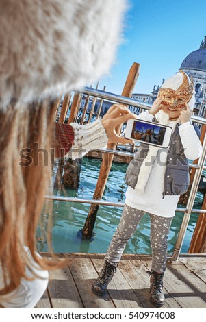 Another world vacation. modern mother in Venice, Italy taking photo of child wearing Venetian mask