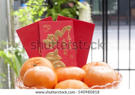 Happy Chinese New Year. "the year of the rooster with prosperity" with oranges in glass bowl top up with golden coins and green leaves red envelope for healthy and wealthy fortune year